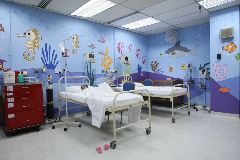 A pediatric hospital room with ocean-themed wall art and hospital beds.