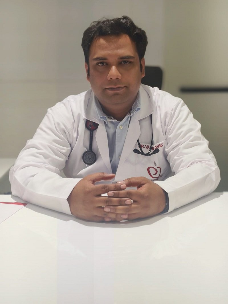 Dr. Varun Garg in a white coat sitting at a table, ready for consultation.